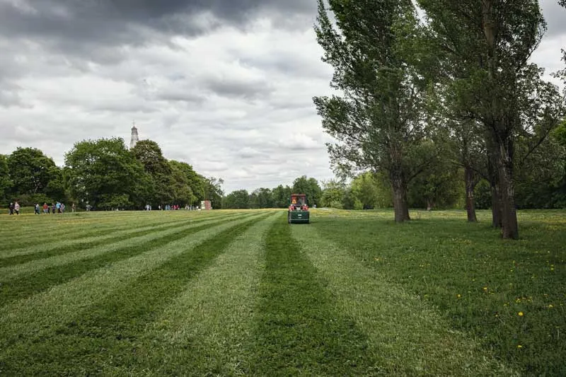 Lawn mower cutting grass in a park.